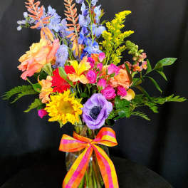 Colorful mixed bouquet in a glass vase with a striped ribbon