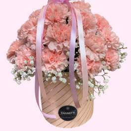 Pink carnations in a hatbox with lavender ribbons and a heart topper