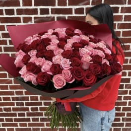 Large bouquet of red and pink roses wrapped in burgundy paper