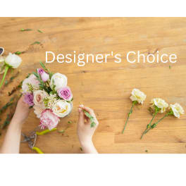Hand arranging a pastel bouquet of roses and carnations on a wooden table