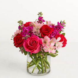 Bouquet of red and pink roses with pale pink lilies in a glass vase