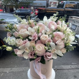 Large blush and white floral arrangement in a round box with ribbon
