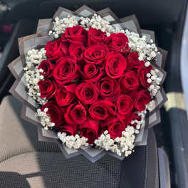 Bouquet of red roses with white baby's breath in dark wrap