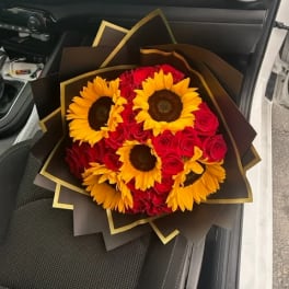 Bouquet of red roses and yellow sunflowers wrapped in dark paper
