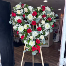 Heart-shaped floral wreath of red and white roses on a wooden easel