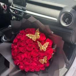 Bouquet of red roses wrapped in black paper with butterfly decorations