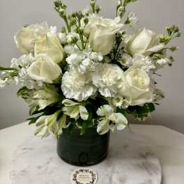 White roses and carnations arranged in a dark green vase