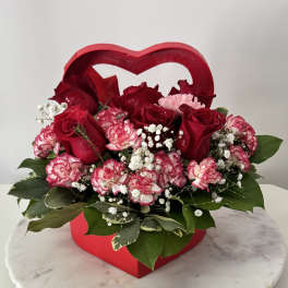 Heart-shaped red box filled with red roses and pink carnations
