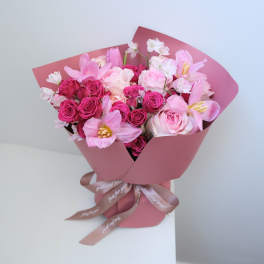 Pink bouquet of roses and tulips wrapped in pink paper