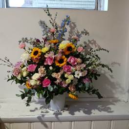 Large mixed bouquet in a white vase with pink, yellow, and blue flowers