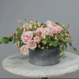 Pink roses and small blossoms in a gray ribbed container