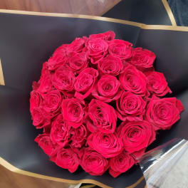 Bouquet of bright pink roses wrapped in black paper with gold trim