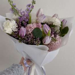 Handheld bouquet of pink and white flowers wrapped in white paper