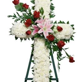 White floral cross with red roses and pink lilies on an easel