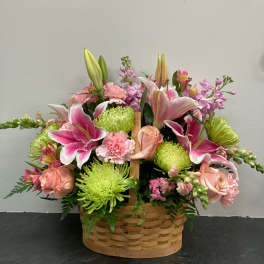 Basket arrangement of pink lilies, roses, carnations, and green chrysanthemums