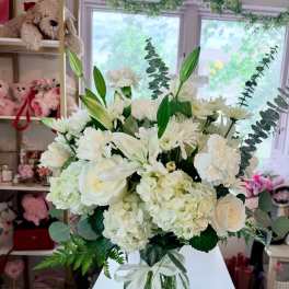White floral bouquet in a clear glass vase with a ribbon