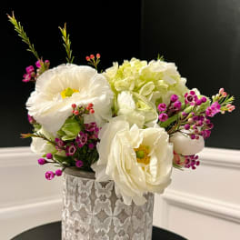 White flowers and pink filler in a textured silver vase