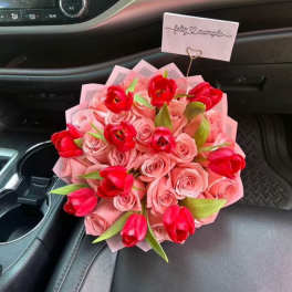 Bouquet of pink roses and red tulips with a small card