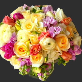 Mixed bouquet of pastel roses and ranunculus in a glass vase
