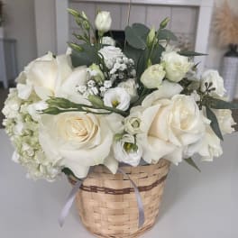 White rose bouquet in a woven basket with eucalyptus accents