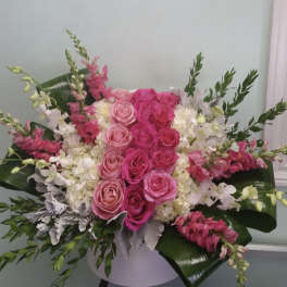 Pink and white rose arrangement with snapdragons in a white vase