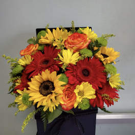 Bright mixed bouquet of red and yellow flowers in a black gift box