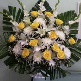 Yellow roses and white lilies arranged with palm leaves