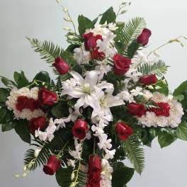 Standing floral cross with red roses, white lilies, and white orchids