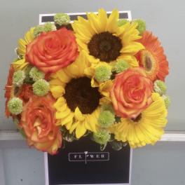 Bouquet of sunflowers, orange roses, and green button mums in a black box