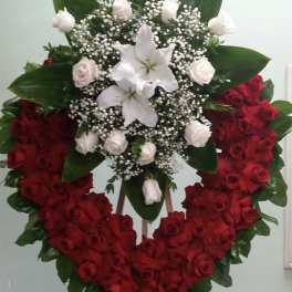 Heart-shaped red rose wreath with white lilies and roses on an easel