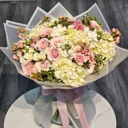 Bouquet of pink and white roses with hydrangeas wrapped in translucent paper