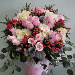 Pink roses and white hydrangeas in a pink hatbox arrangement