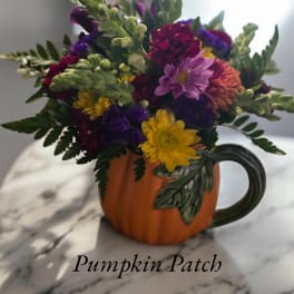 Mixed flowers arranged in a pumpkin-shaped mug