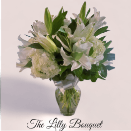 White lilies and hydrangeas in a glass vase with a silver ribbon