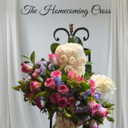 Floral cross arrangement with pink and white roses on a black stand