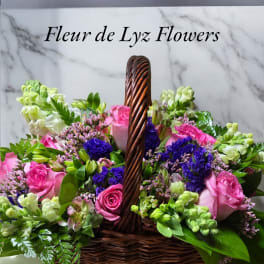 Pink and white flowers arranged in a wicker basket