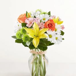 Bouquet of mixed flowers in a clear glass vase with a ribbon