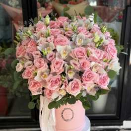 Pink roses and white orchids arranged in a pink hat box