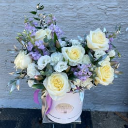 Cream roses and lavender flowers in a white hat box