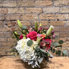 Bouquet of pink roses, white hydrangea, and lilies in a glass vase