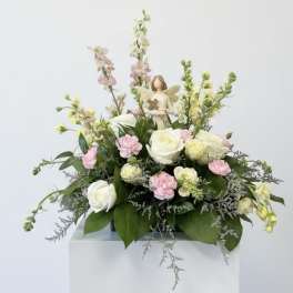 Pastel floral arrangement with roses and carnations on a pedestal