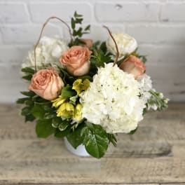 Peach roses and white hydrangea in a white container