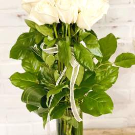 White roses in a glass vase with a white ribbon