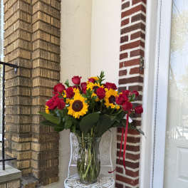 Bouquet of red roses and sunflowers in a clear glass vase