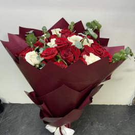 Bouquet of red and white roses wrapped in burgundy paper