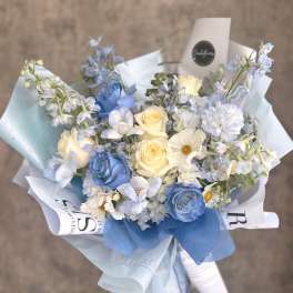 Bouquet of blue and cream roses with pale blue flowers wrapped in paper