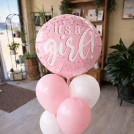 Pink and white balloon bouquet with a round balloon reading "it's a girl"