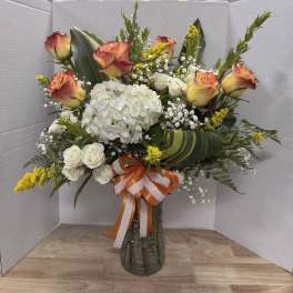 Bouquet of roses, hydrangea, and white filler flowers in a glass vase