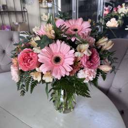 Pink gerbera and mixed blooms in a clear glass vase
