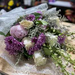 Bouquet of purple and white flowers wrapped in lace paper
